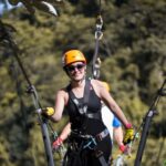 Guest wearing safety helmet and harness crossing a suspension bridge during a zipline tour in Puerto Rico rainforest